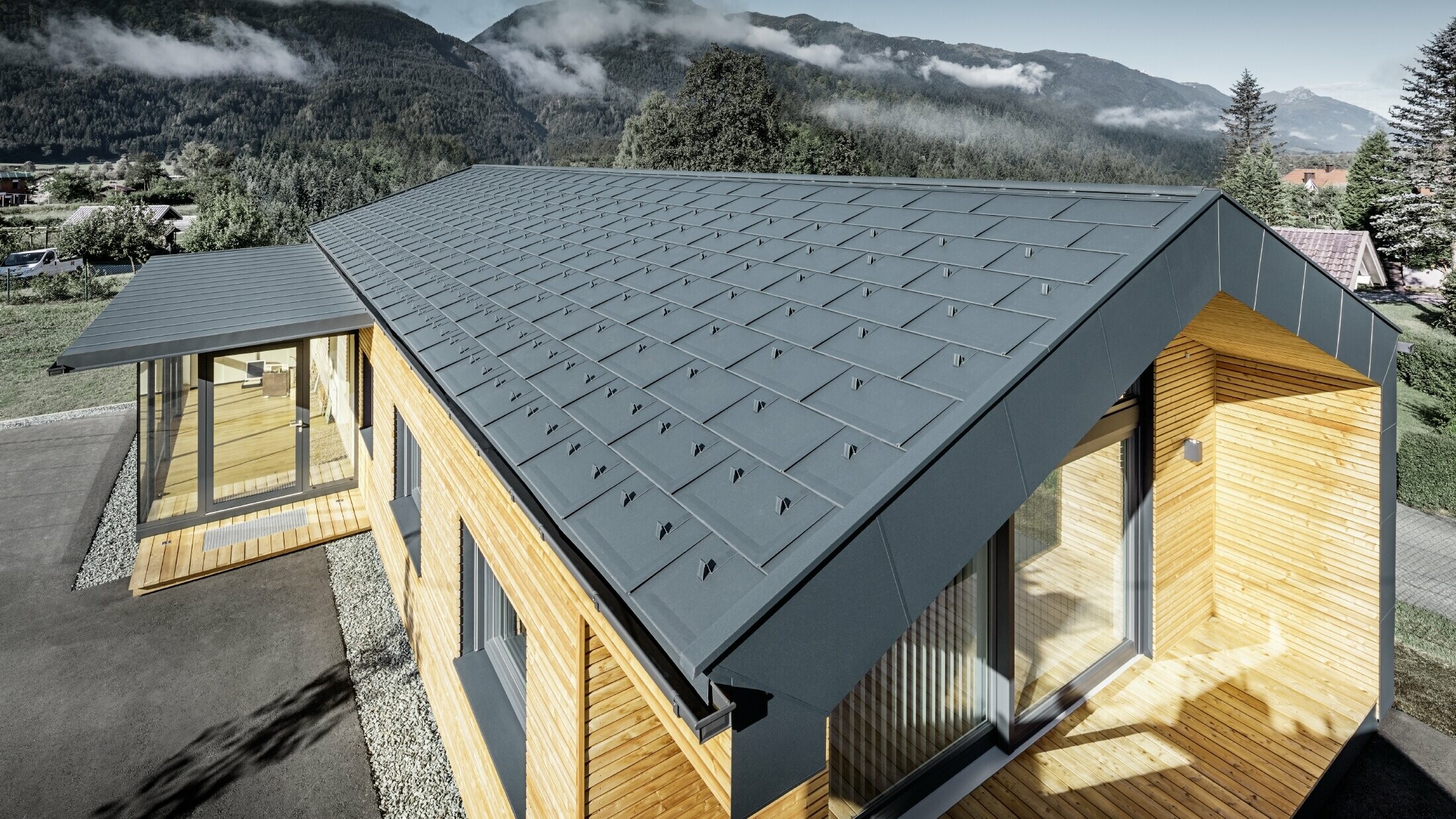 Nuovo edificio per uffici di Holzbau Faltheiner con facciata in legno di larice, ampie finestre e tetto PREFA color antracite.