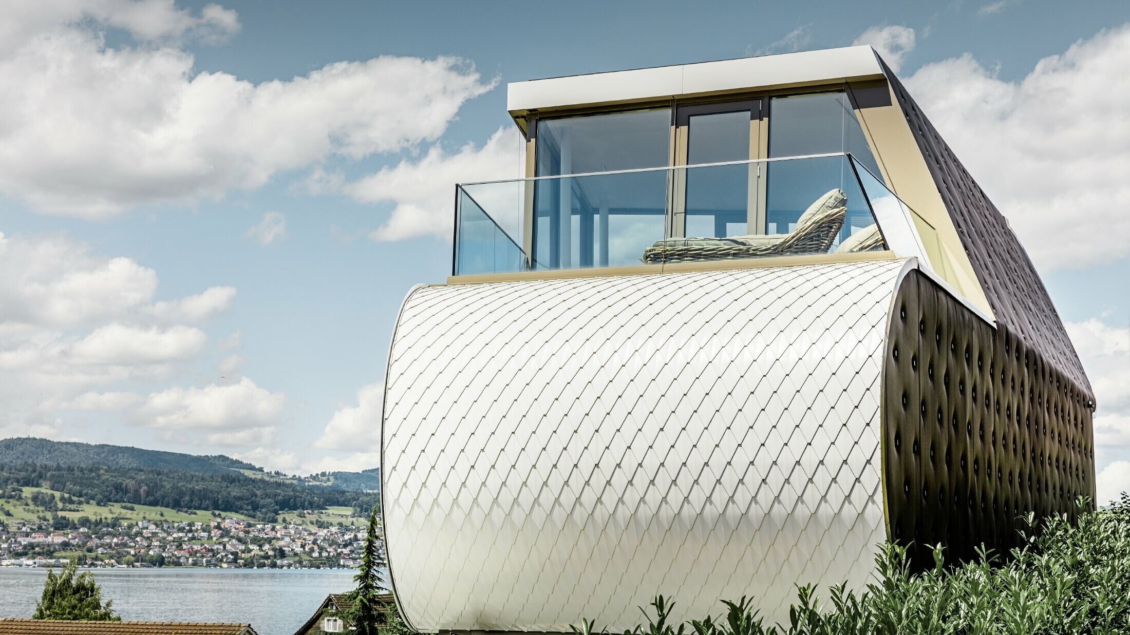 Vista laterale della splendida Flexhouse, progettata dall'architetto Camenzind; è possibile notare una delle pareti esterne curve rivestita con la facciata in alluminio squamato PREFA bianco puro.