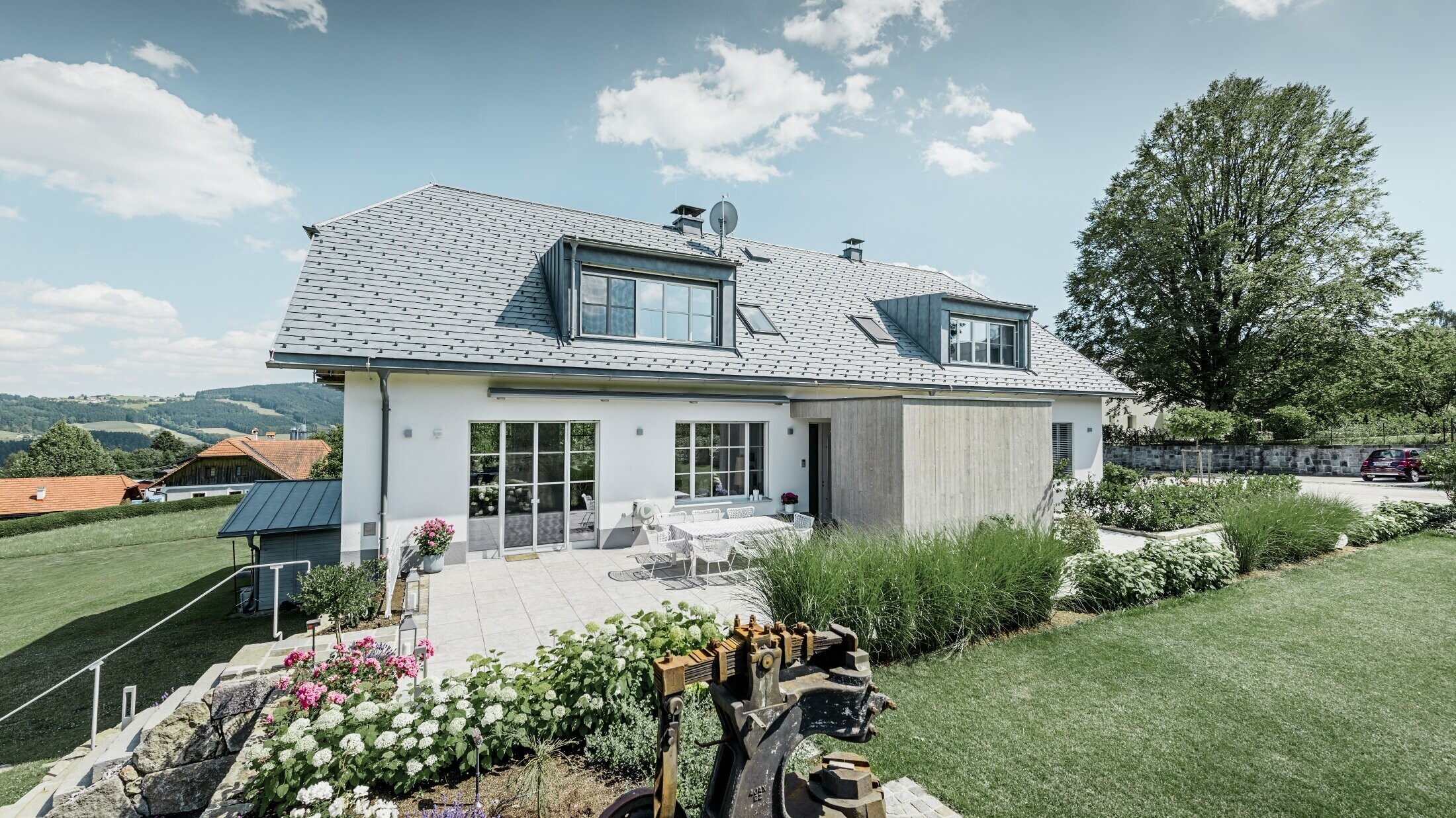 Classica casa unifamiliare con tetto a mezza anca. La casa è stata ristrutturata con scandole PREFA in grigio pietra, con un bel giardino e un’ampia terrazza.