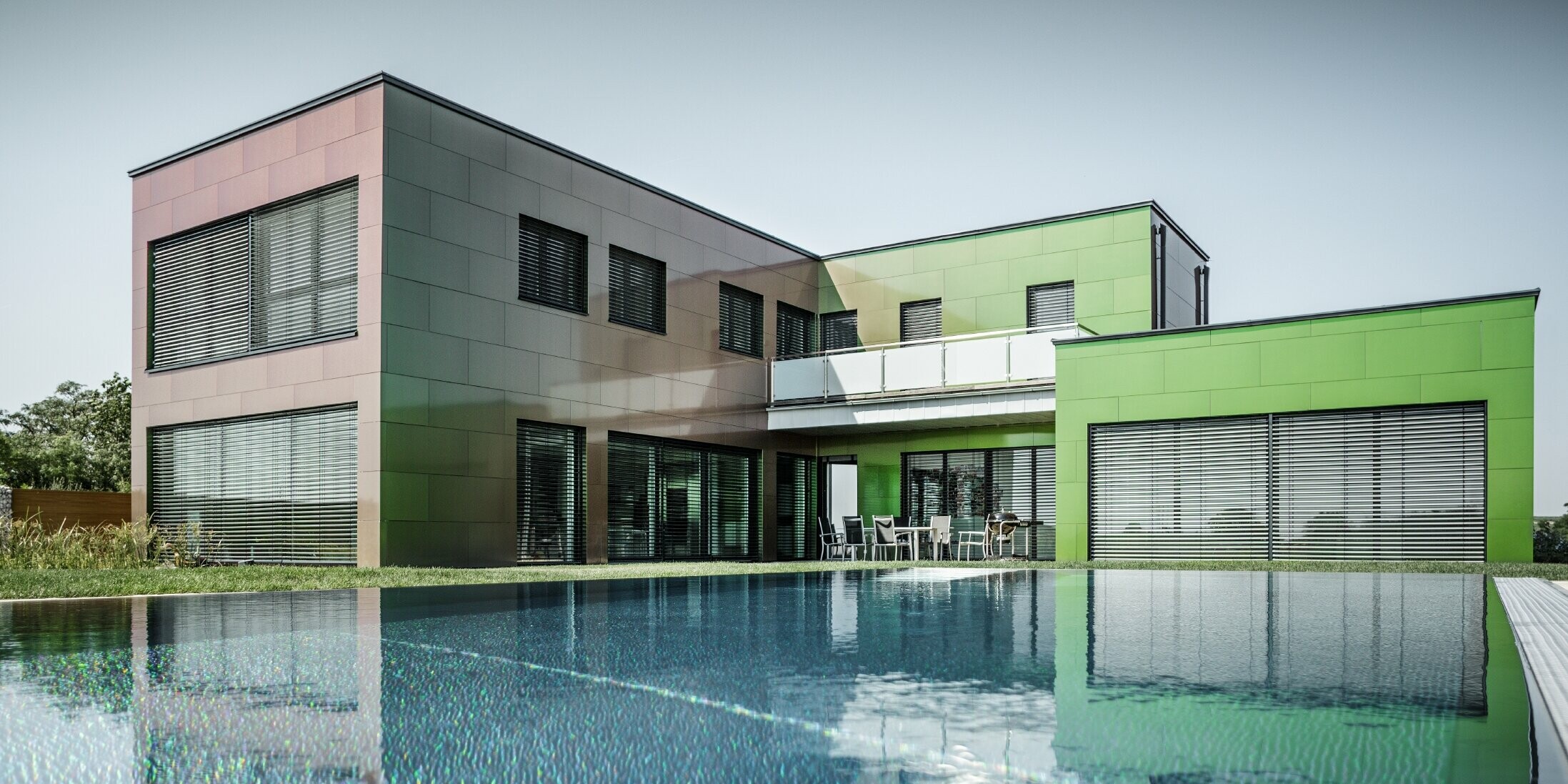 Modernes Einfamilienhaus mit Flachdach uns großem Swimming Pool; Die Fassade ist mit PREFA Aluminium Verbundplatte in der Sonderfarbe Chameleon Spring Lake verkleidet.