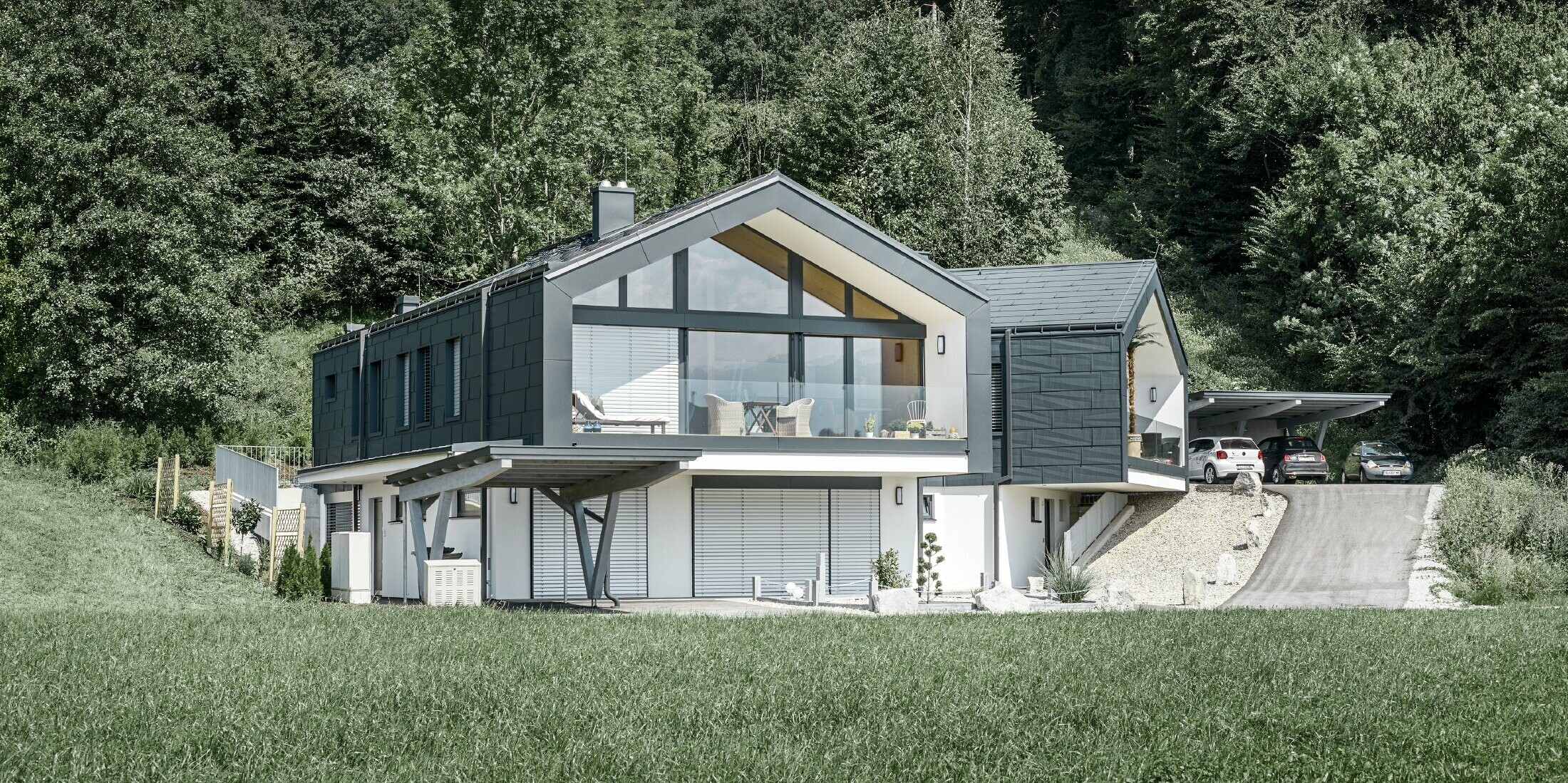 Modernes Mehrfamilienhaust mit einer großen Fensterfront, Dach und Fassade wurden mit dem Dach- und Fassadenpaneel FX.12 in anthrazit von PREFA bekleidet