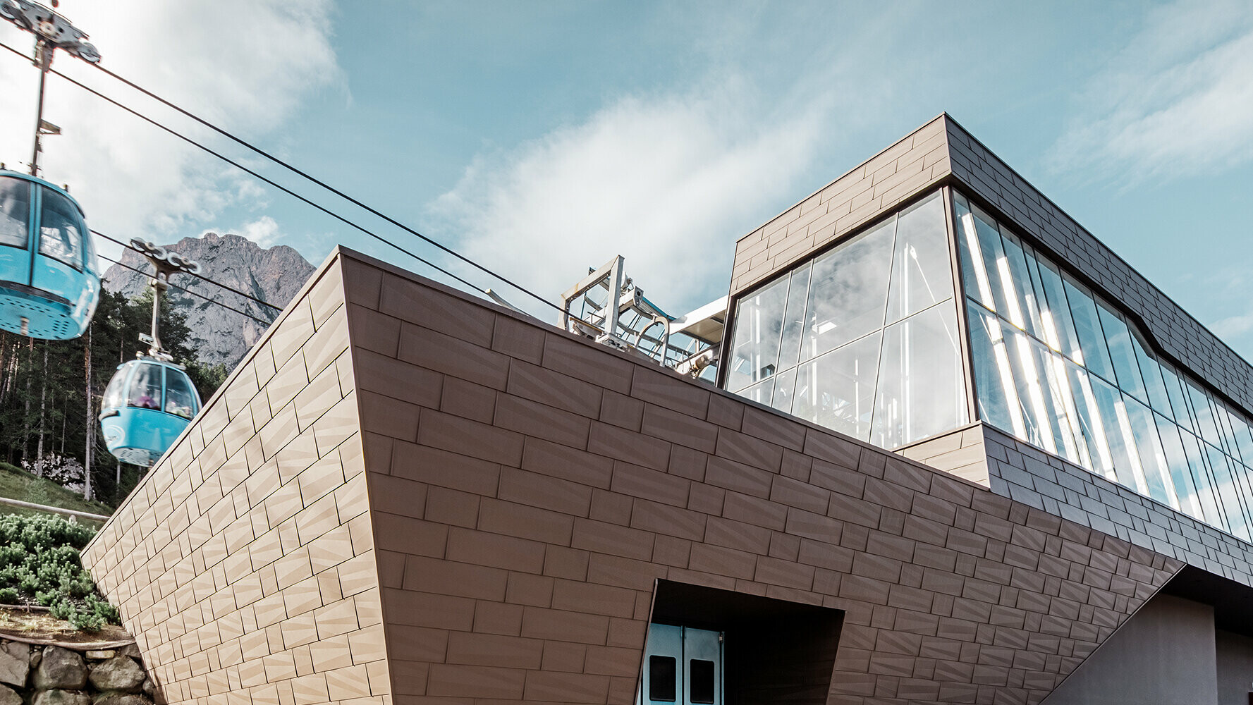 Stazione a valle di una cabinovia in Alto Adige con moderno rivestimento di tetto e facciata di PREFA nel colore marrone.