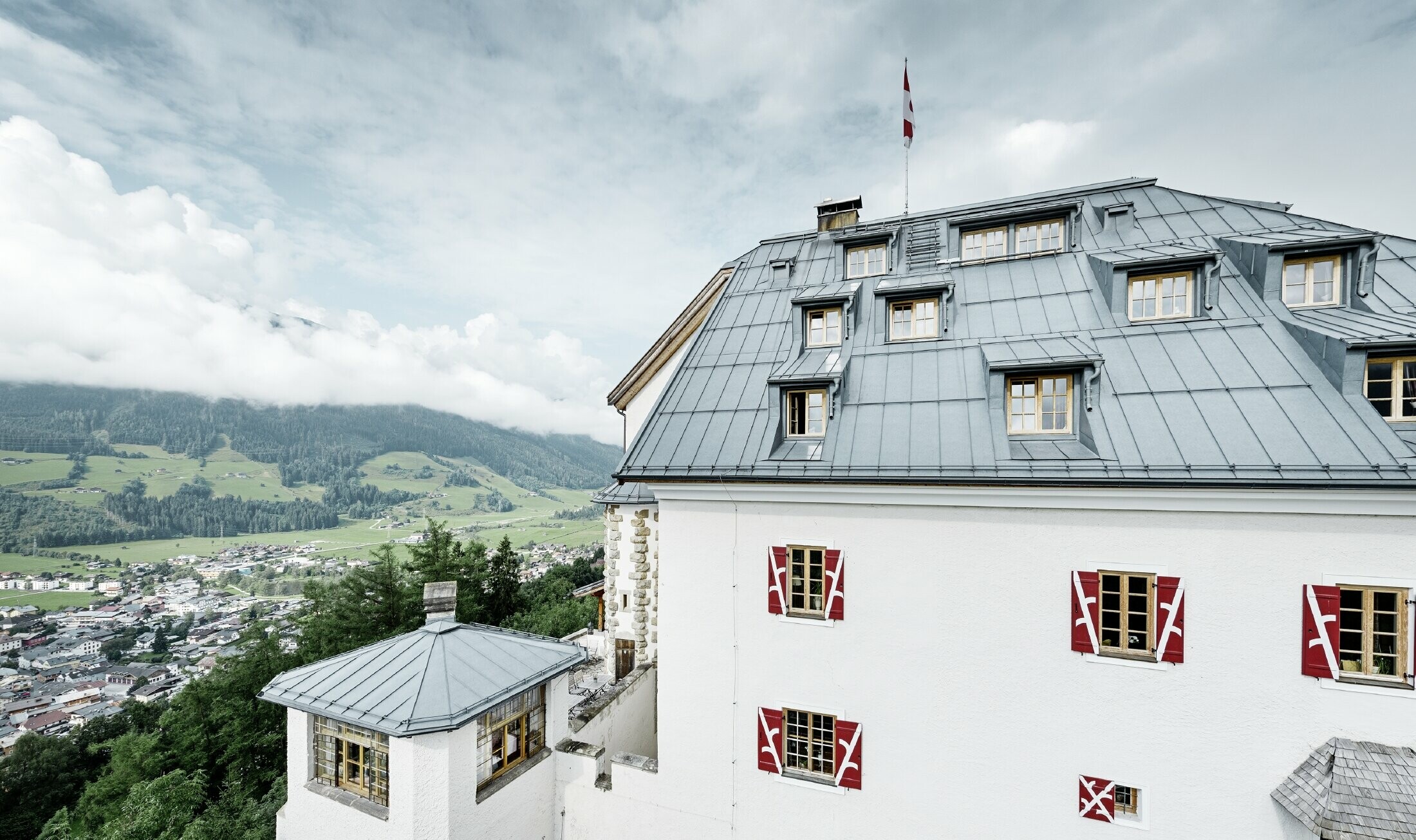 Castello Mittersill circondado da alberi e montagne con una copertura in Prefalz in grigio pietra ristrutturato