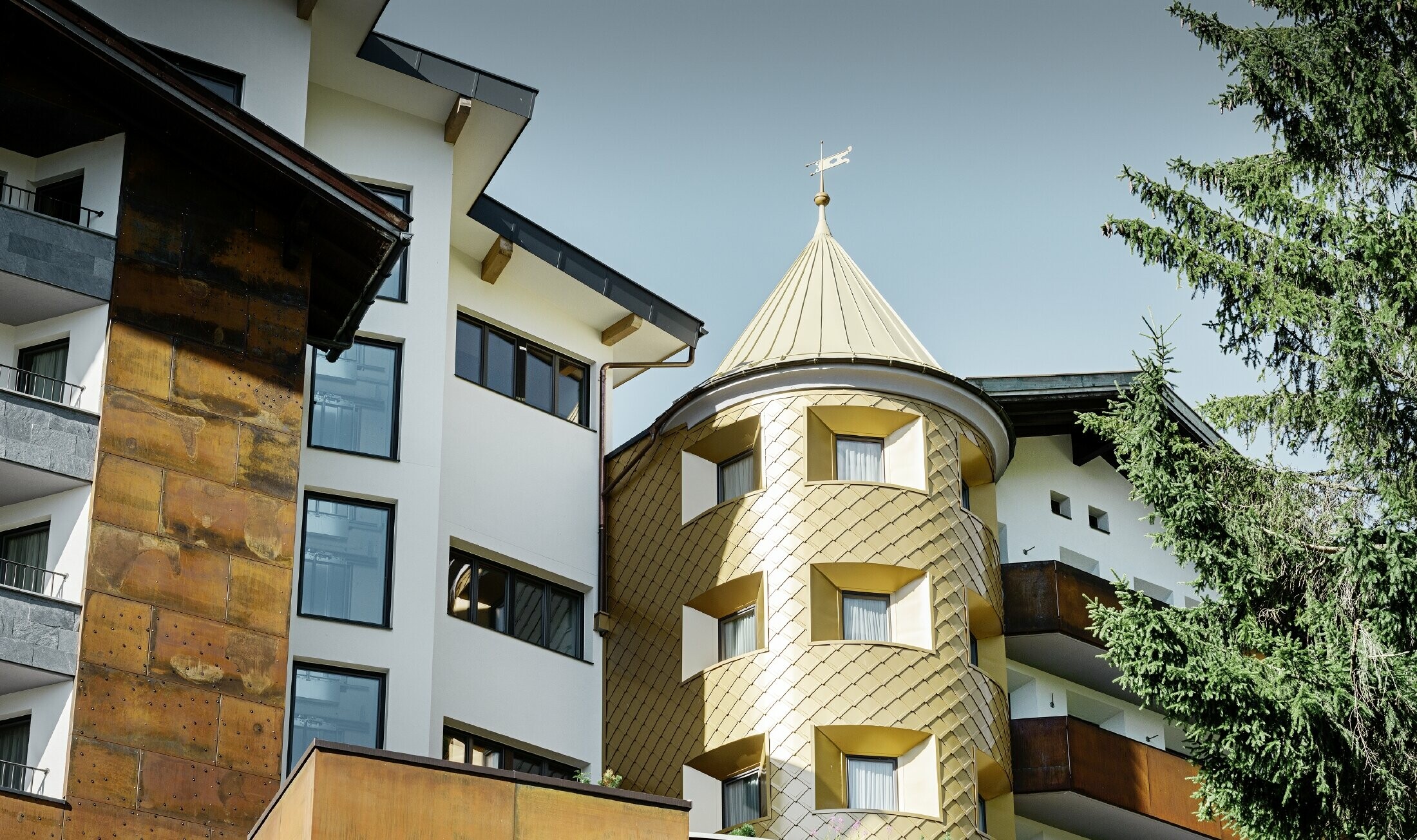 hotel tradizionale a Ischgl con balconi in legno e facciata in legno e una torre in scaglie PREFA in oro