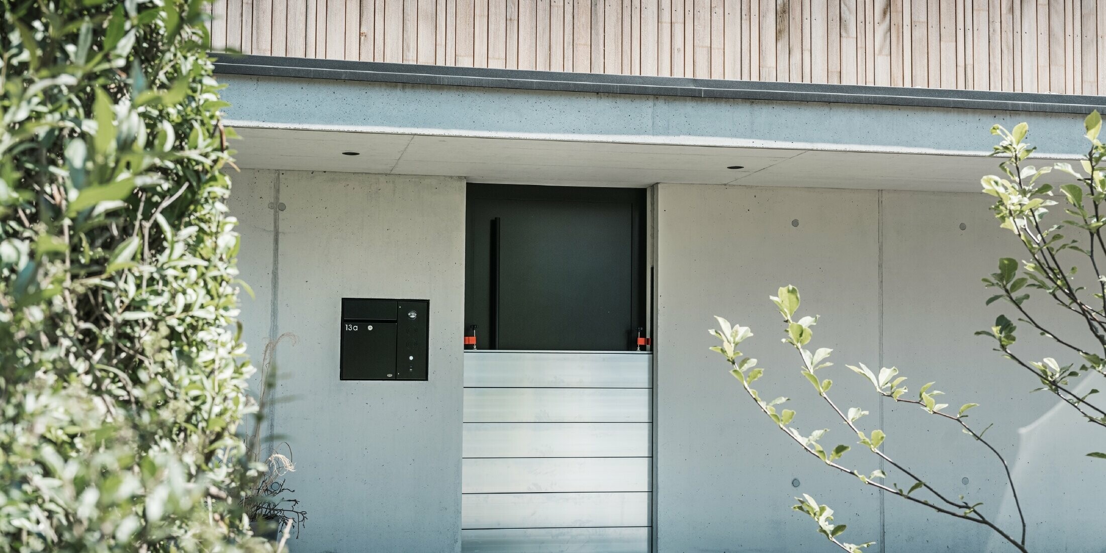 La protezione antiallagamento PREFA è installata davanti alla porta d'ingresso di una casa indipendente con facciata in legno. 