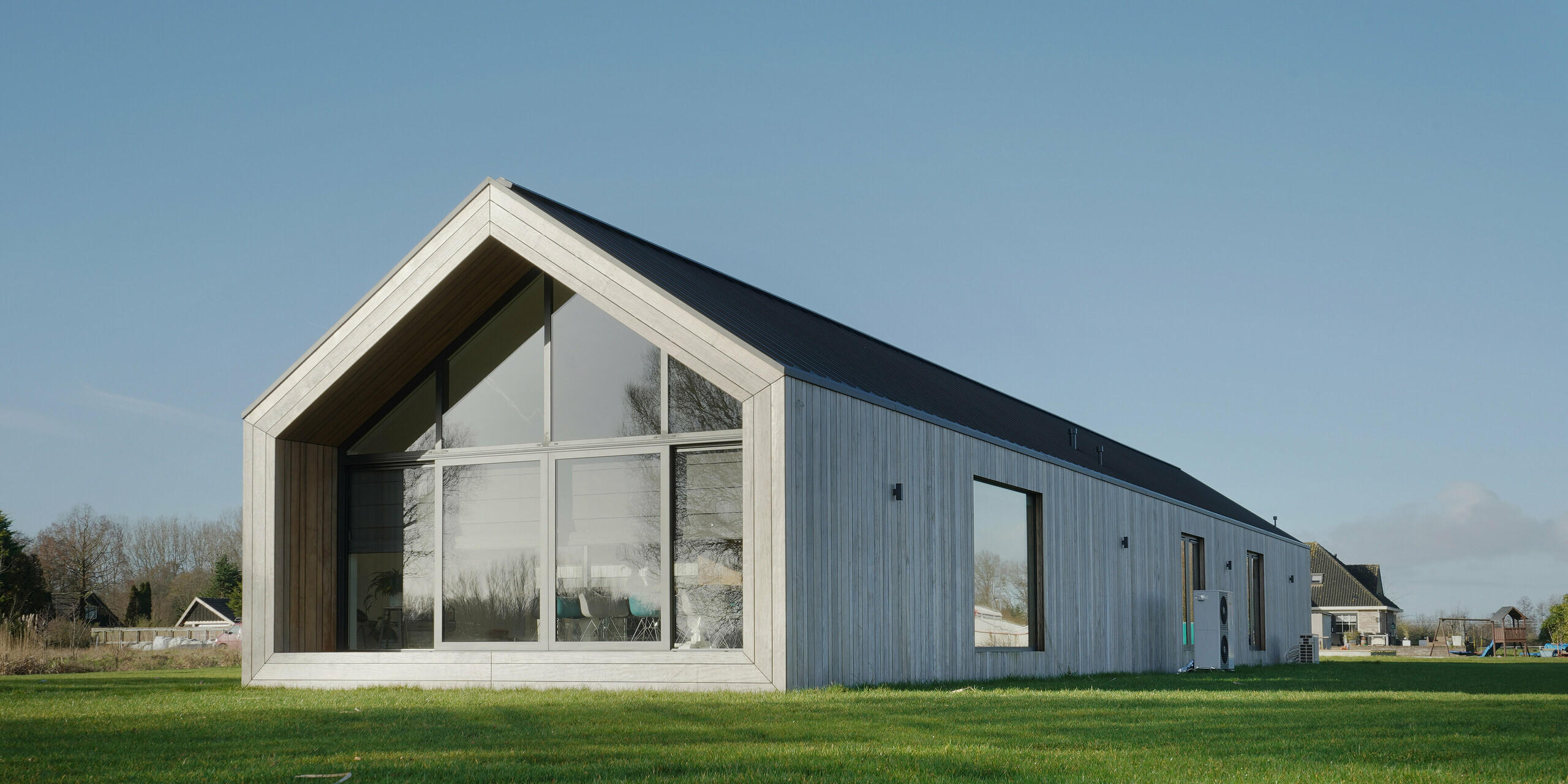 Modernes Einfamilienhaus im Design einer klassischen Scheune mit PREFALZ Dach in Uithoorn, Niederlande. Die minimalistische Architektur kombiniert großzügige Glasfronten mit einer langlebigen und witterungsbeständigen Aluminiumbedachung von PREFA. Die natürliche Holzfassade ist die perfekte Ergänzung an der Gebäudehülle. Das Satteldach verleiht dem Haus einen klassischen Look, während die klaren Linien und das hochwertige Blechdach für Langlebigkeit und zeitlose Eleganz sorgen. Ideal für innovative Bauprojekte, die auf Ästhetik und Qualität setzen.
