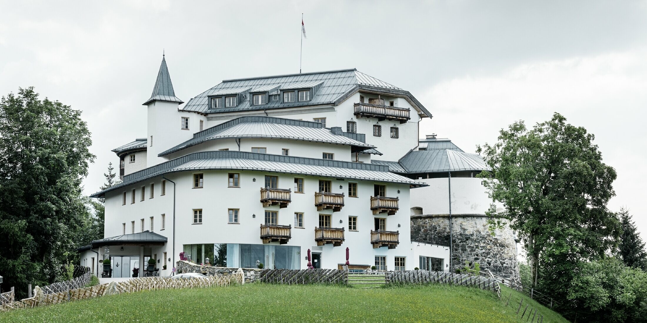 Schloss Mittersill, umgeben von Bäumen und Bergen, mit einem renovierten Prefalz Dach in Steingrau