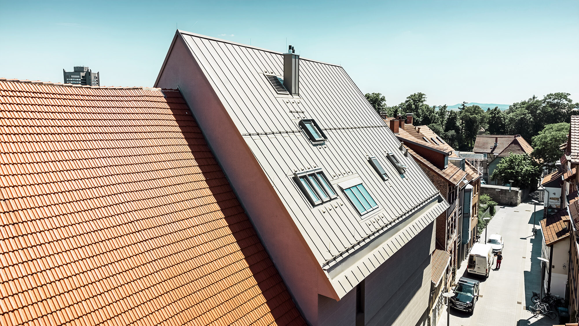 Vista laterale sull'insolita copertura, accanto gli edifici con le tegole piane di colore rosso ruggine.