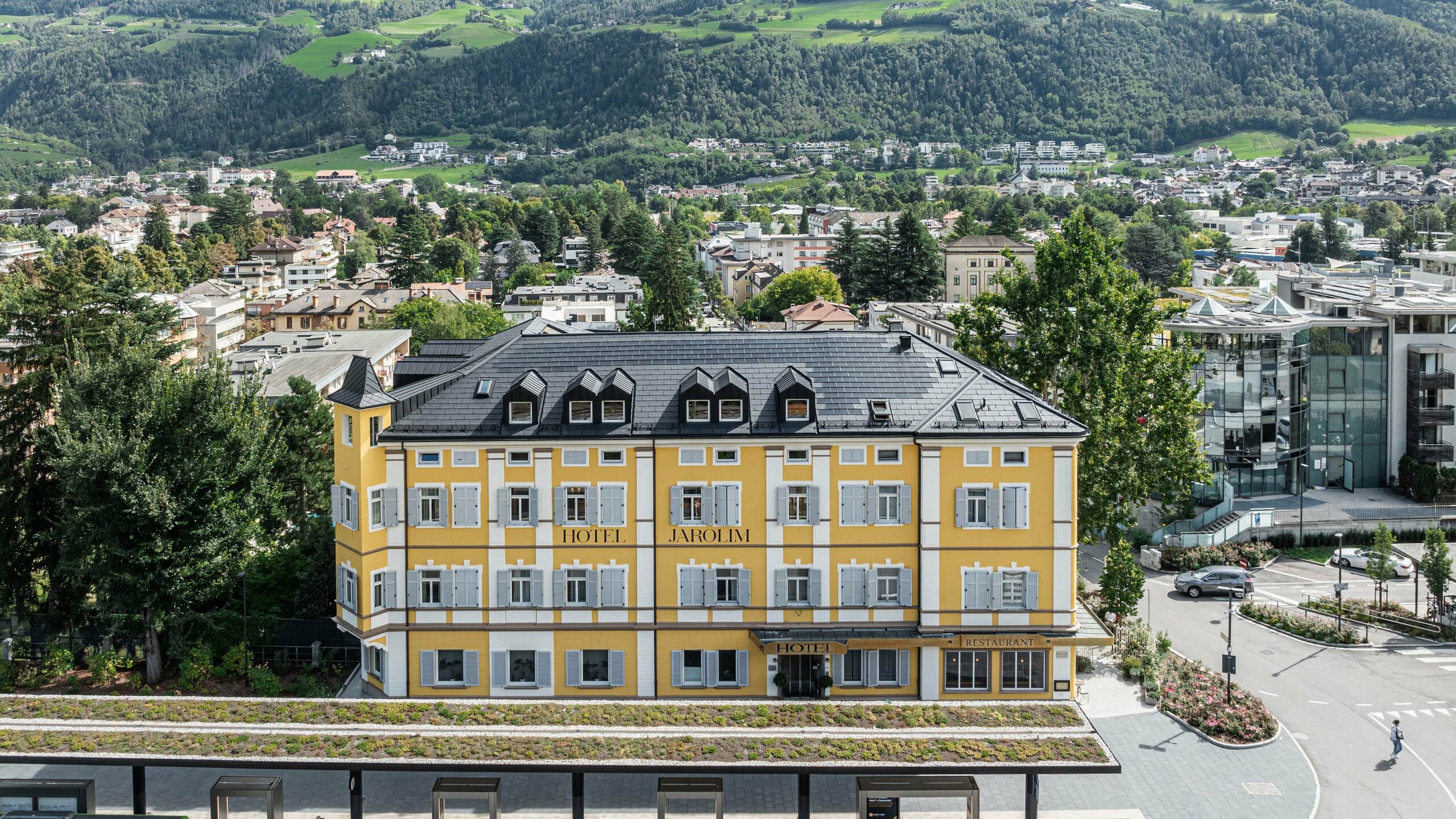 Vista dall'alto dello storico Hotel Jarolim ristrutturato in tegole fotovoltaiche PREFA a Bressanone.