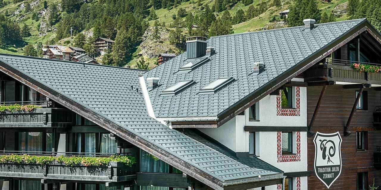 Hotelalpenhof in Zermatt mit dem Matterhorn im Hintergund, Balkonen, dunkler Holzfassade und einem PREFA Aluminiumdach in anthrazit