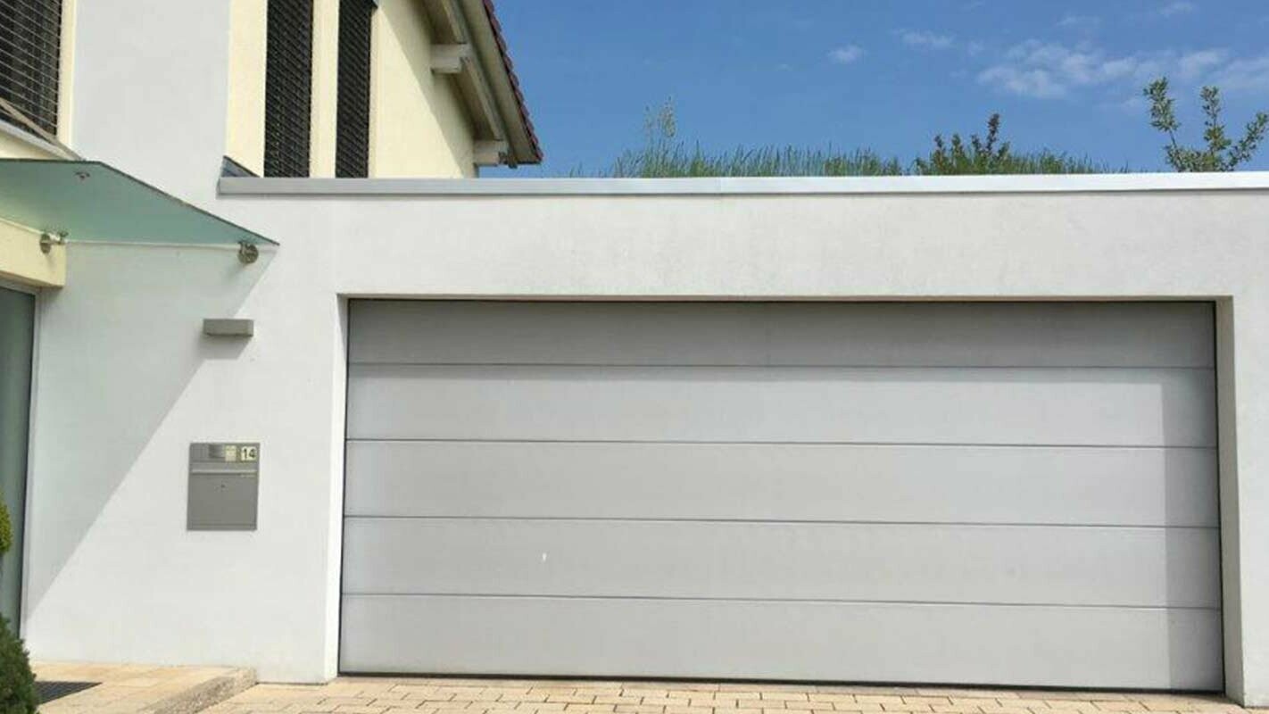 Garage prima della ristrutturazione con doghe di rivestimento PREFA color antracite, facciata bianca e portone bianco