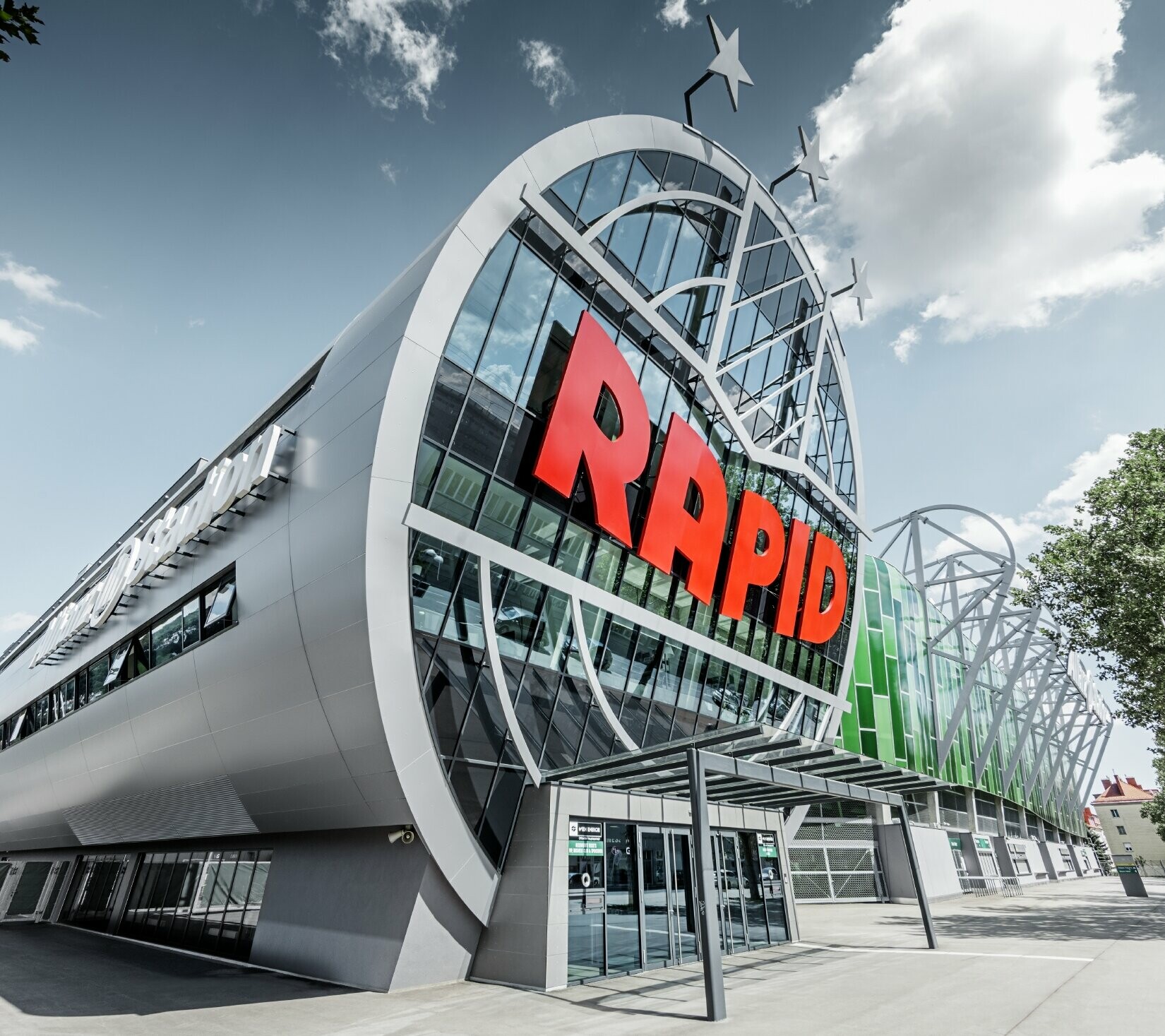 Der Eingang ins Allianz Stadion mit dem großen SK Rapid Wien Logo; Die Röhre mit der großen Glasfront ist mit der PREFA Aluminium Verbundplatte in Silbermetallic eingedeckt.