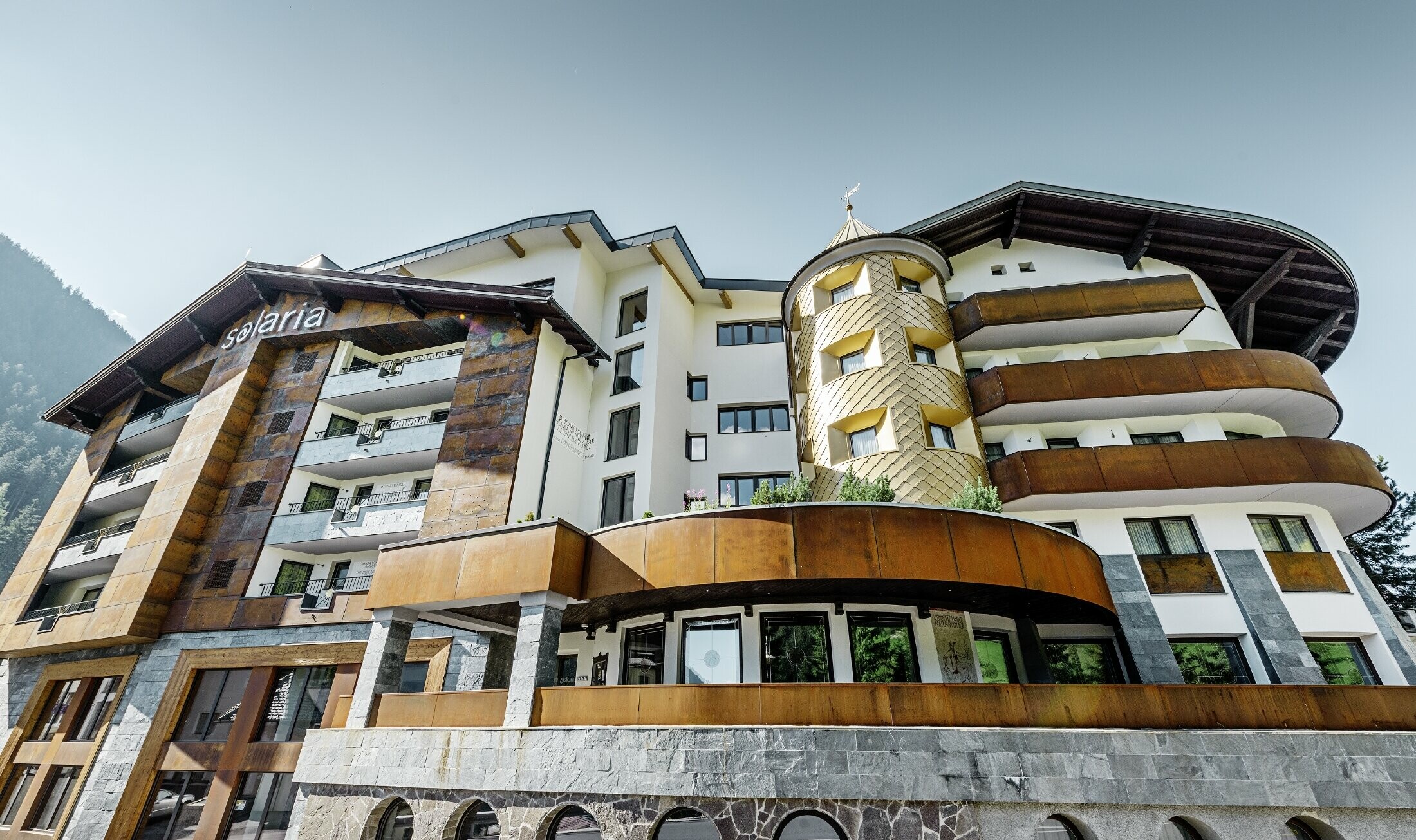 hotel tradizionale a Ischgl con balconi in legno e facciata in legno e una torre in scaglie PREFA in oro