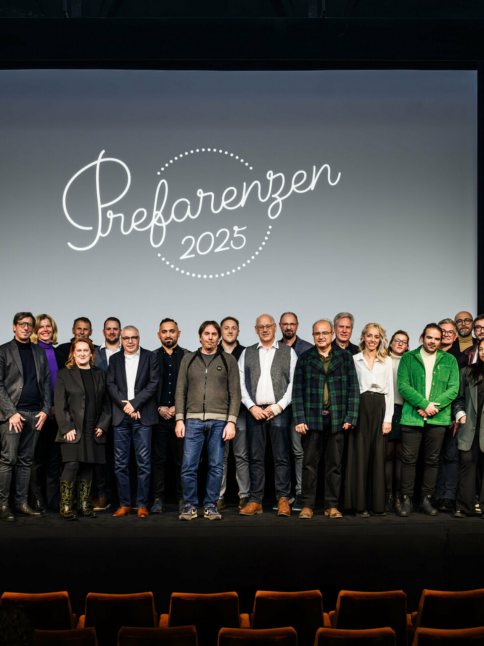 Gruppenfoto bei der PREFARENZEN-Premiere 2025 im Stadtkino Wien: Jürgen Jungmair, Marketingleiter von PREFA, mit den Mitwirkenden und Gästen vor dem Logo der Veranstaltung ‚Prefarenzen 2025‘ auf der Leinwand. Die Teilnehmer:innen repräsentieren Architektur, Planung, Verarbeitung und Medien aus ganz Europa.