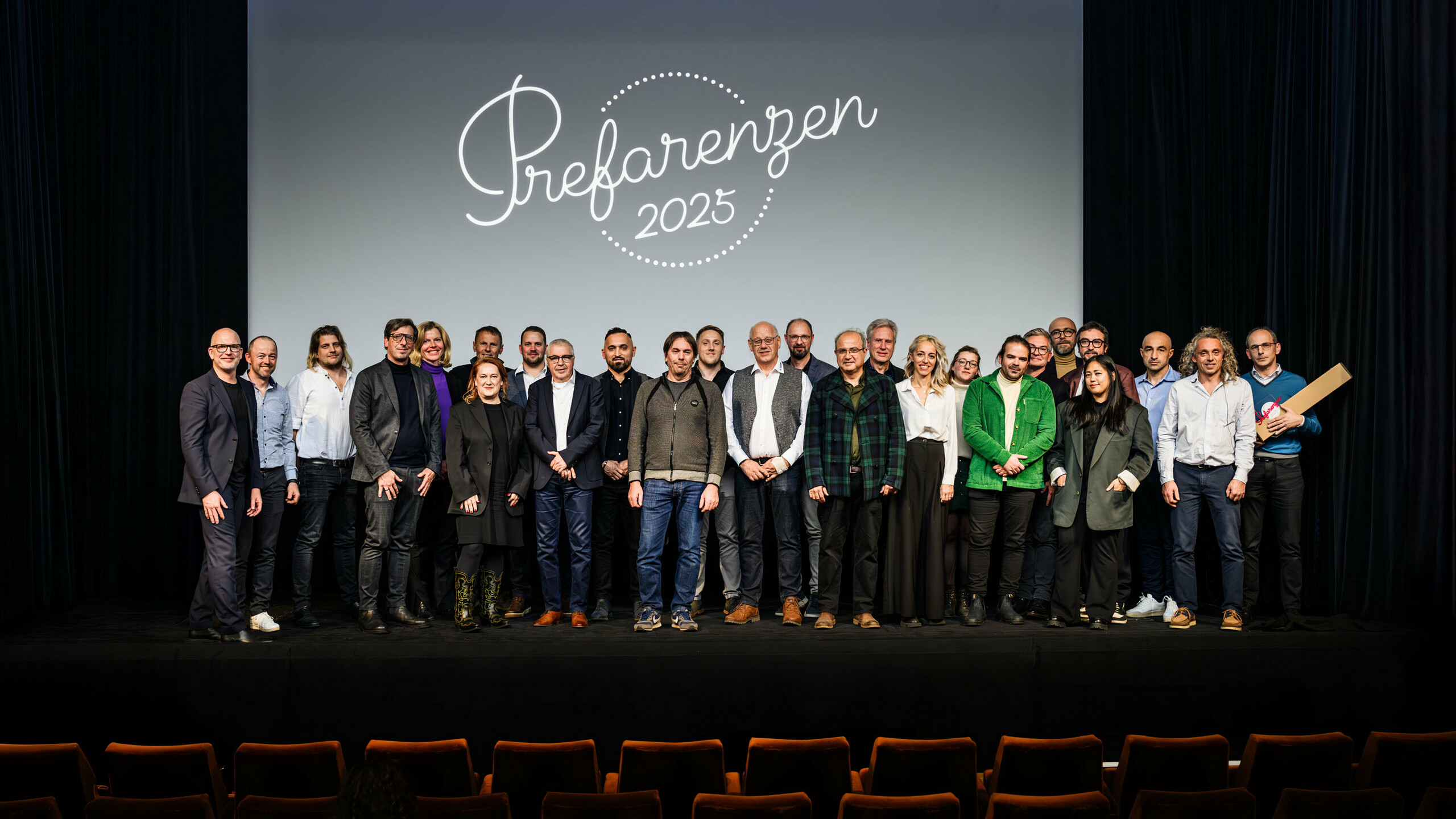 Gruppenfoto bei der PREFARENZEN-Premiere 2025 im Stadtkino Wien: Jürgen Jungmair, Marketingleiter von PREFA, mit den Mitwirkenden und Gästen vor dem Logo der Veranstaltung ‚Prefarenzen 2025‘ auf der Leinwand. Die Teilnehmer:innen repräsentieren Architektur, Planung, Verarbeitung und Medien aus ganz Europa.