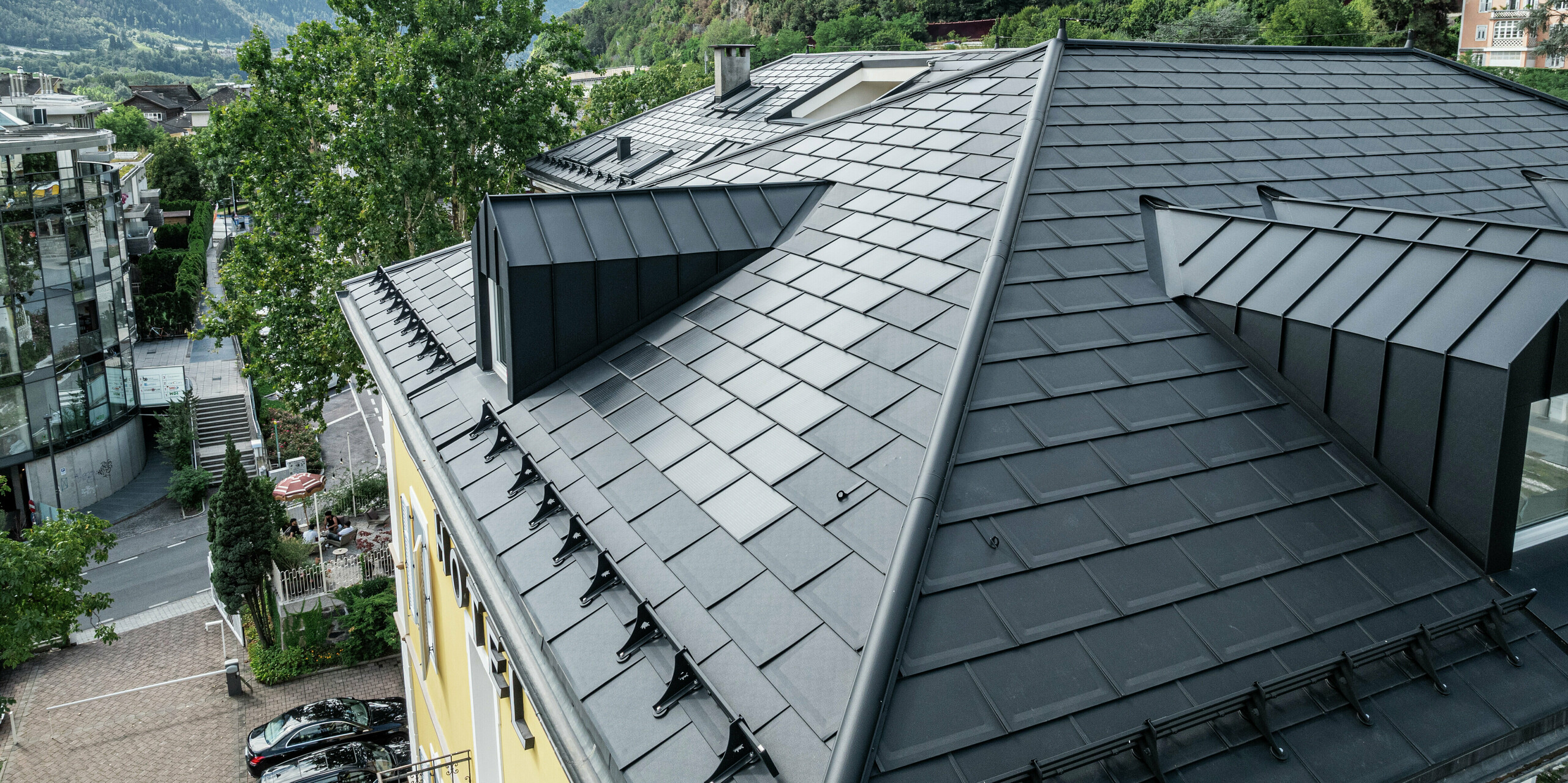 Das PREFA Dach des Hotel Jarolim in Brixen beeindruckt mit innovativen PREFA Solardachplatten und Dachplatten R.16 in modernem P.10 Schwarz. Gauben und weitere Dachdetails wurden präzise umgesetzt, sodass Funktionalität und Ästhetik perfekt vereint sind. Das langlebige und witterungsbeständige Aluminiumdach ist ideal für denkmalgeschützte Gebäude und ermöglicht eine nachhaltige Energiegewinnung, ohne das historische Erscheinungsbild zu beeinträchtigen. Das historische Haus überzeugt mit Qualität und Innovation auf höchstem Niveau.